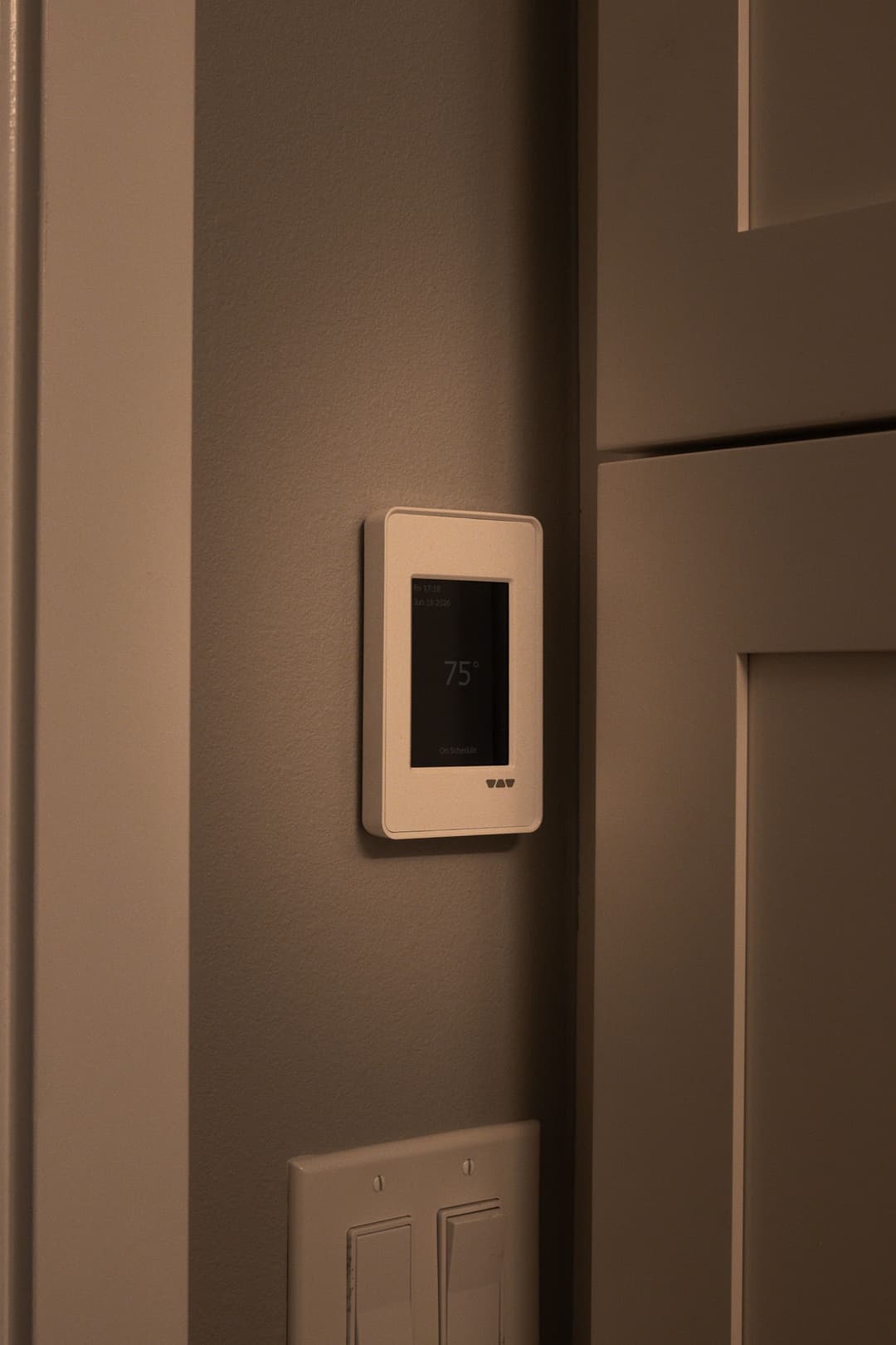 Smart thermostat on a wall displaying temperature setting of 75°F. Modern home climate control.