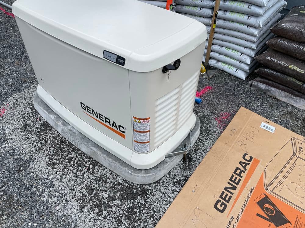 Generac home backup generator on display with packaging and landscape materials in background.