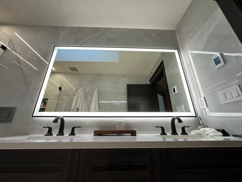 Modern bathroom with illuminated mirror, sleek faucets, and stylish countertop design.