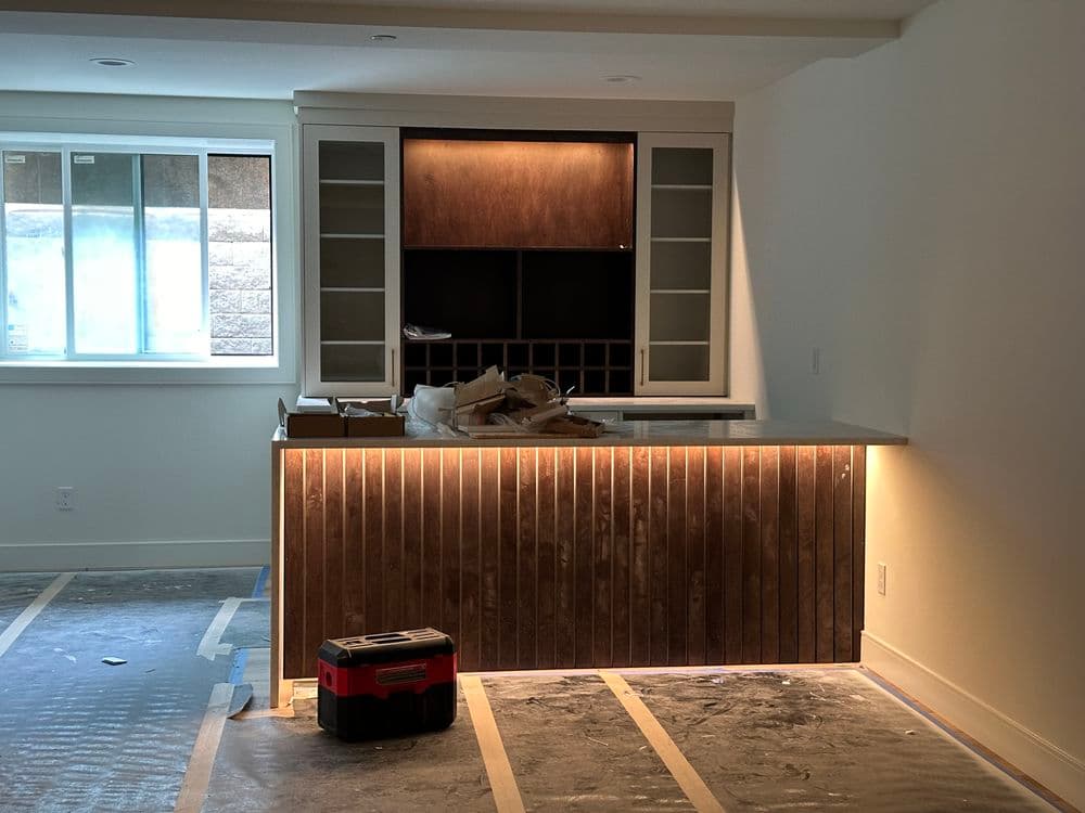 Modern kitchen renovation featuring a sleek island with under-cabinet lighting and wood panels.