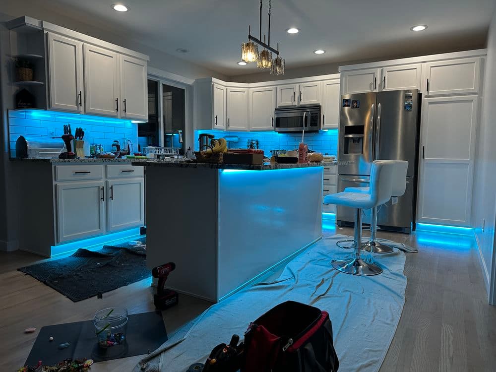 Modern kitchen with blue LED lighting, granite countertops, and stainless steel appliances.