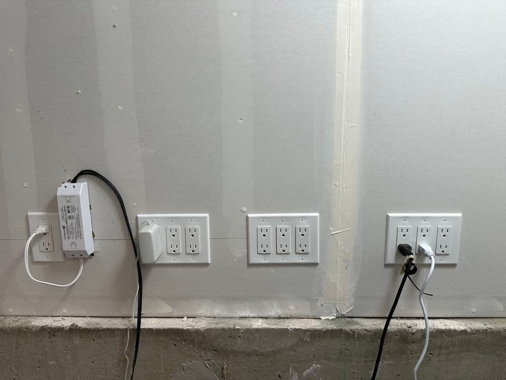 Electrical outlets and wiring installed on a drywall surface in a construction setting.
