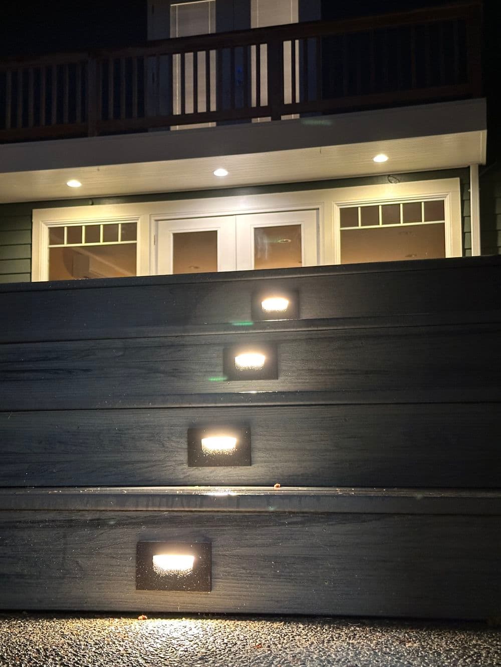 Illuminated outdoor stairs leading to a house entrance with modern lighting at night.