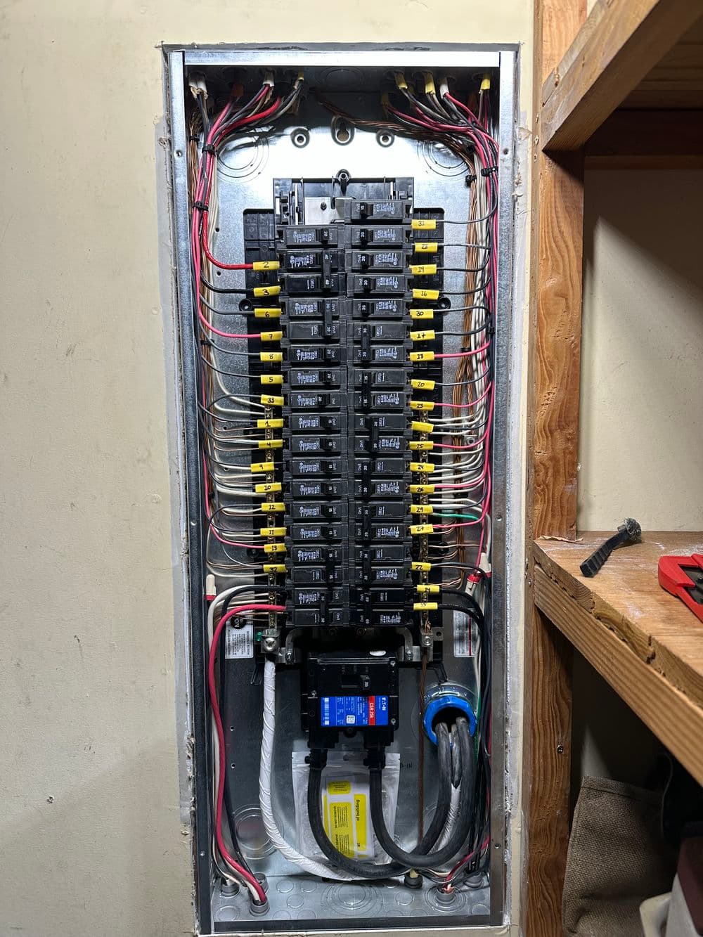 Electrical service panel with multiple circuit breakers and labeled wiring connections.