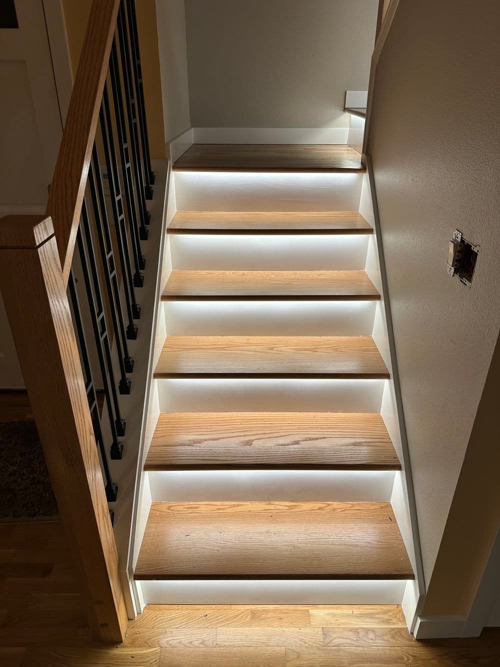 Well-lit wooden stairs with LED lighting, showcasing modern home interior design.