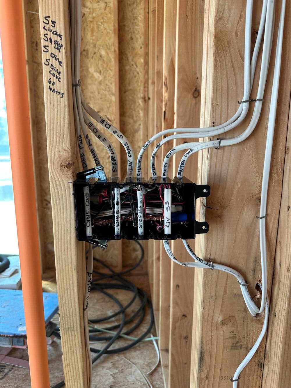 Electrical panel installation with labeled wires in a construction site.