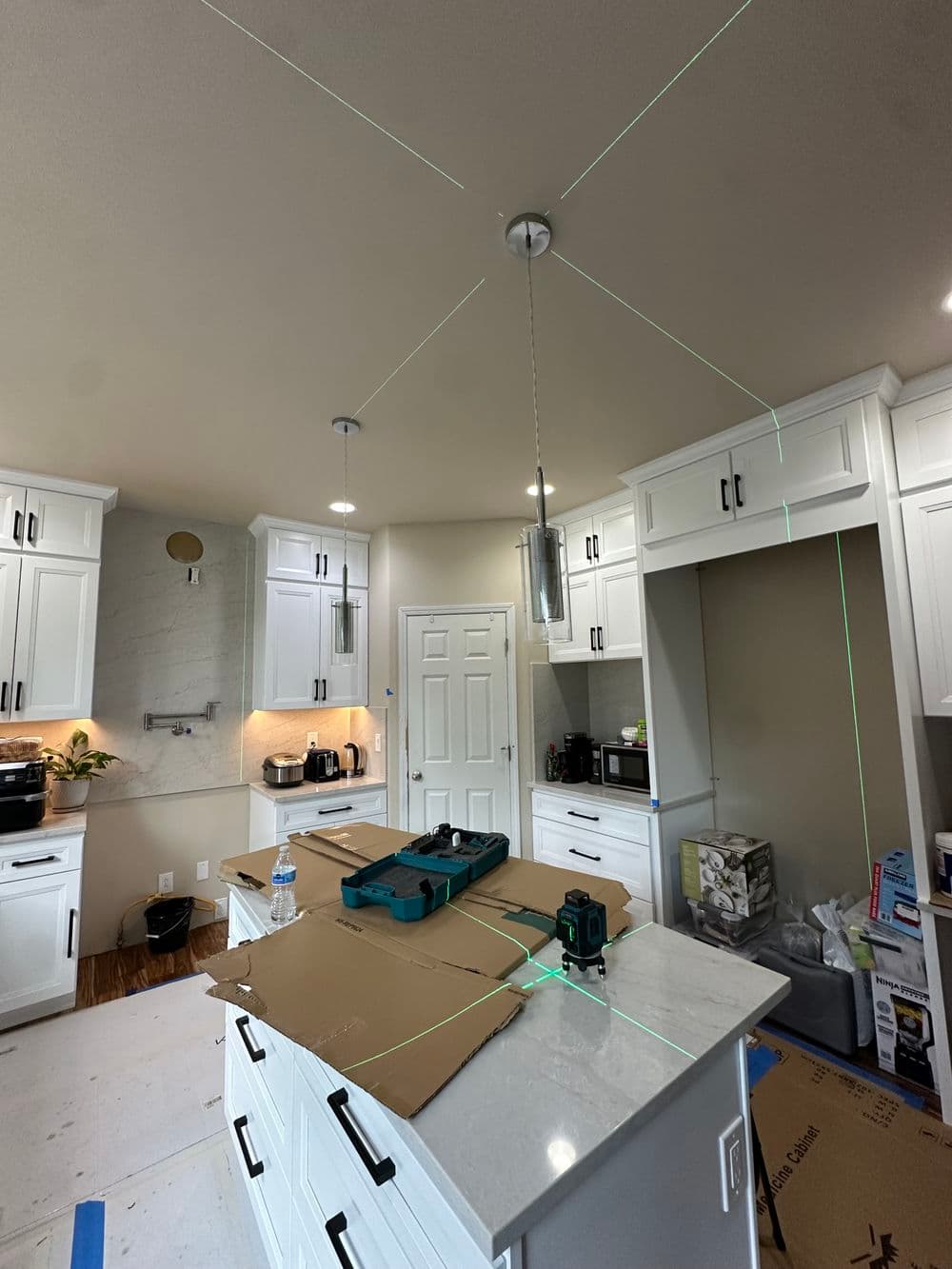Modern kitchen renovation showcasing laser level tools on a countertop with white cabinetry.