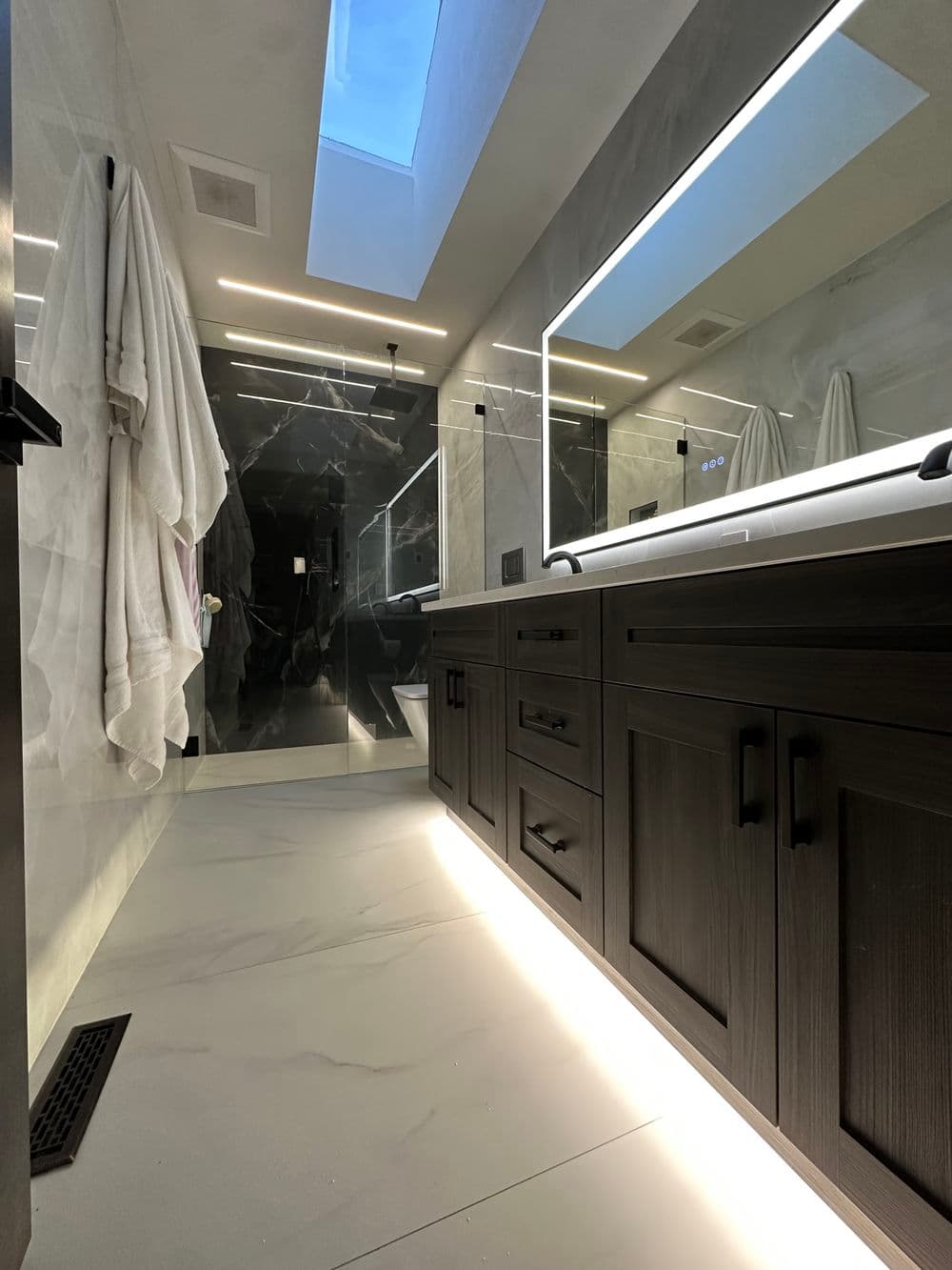 Modern bathroom with a skylight, sleek cabinetry, and stylish lighting features.