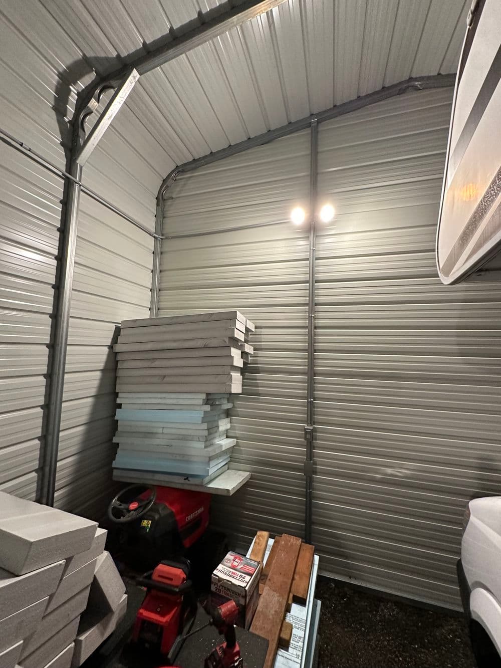 Interior of a storage shed with stacked foam boards and a red tool on a wooden pallet.