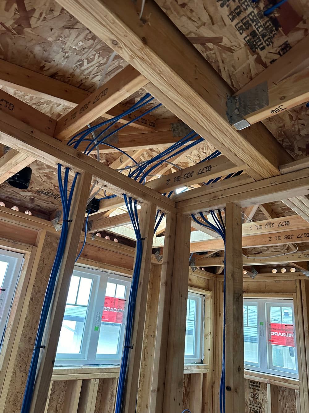 Interior of a home under construction, featuring wooden framing and blue electrical wiring.