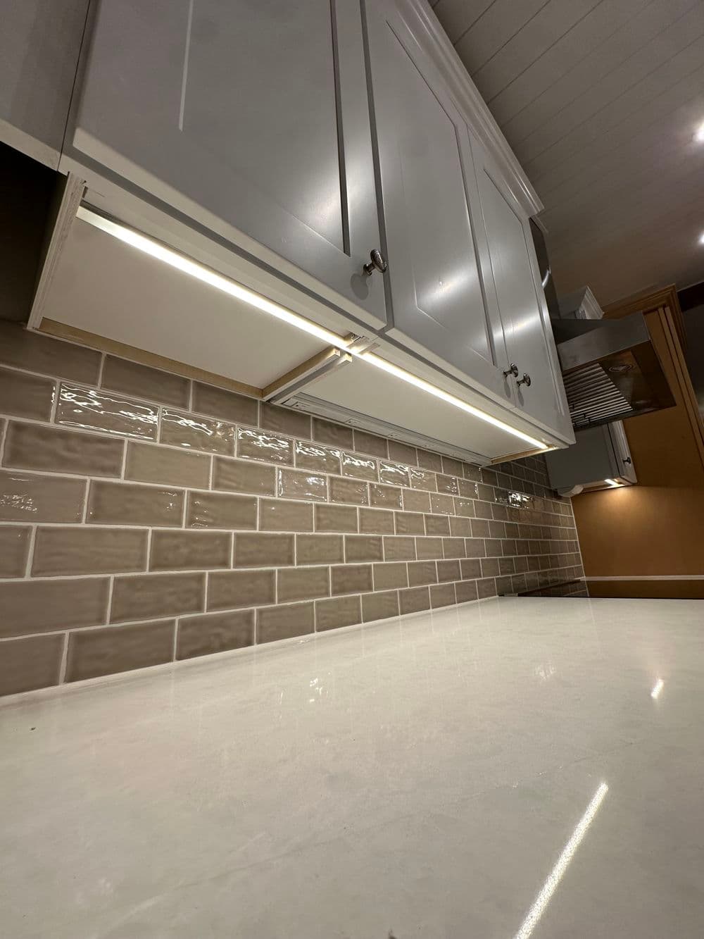 Modern kitchen with gray cabinets and stylish beige backsplash tiles. Bright, sleek countertop design.