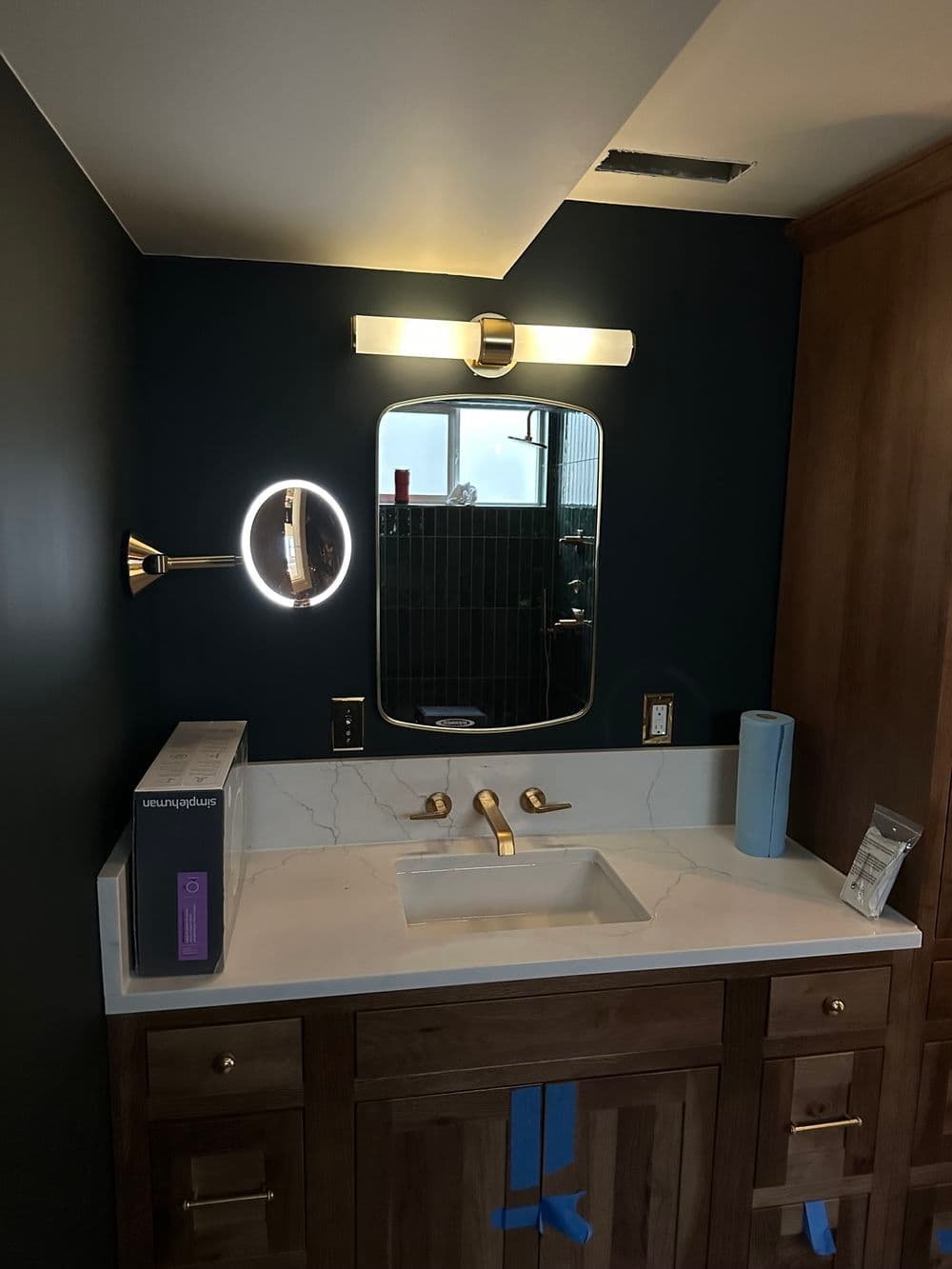 Modern bathroom vanity with round mirror, elegant lighting, and wooden cabinetry.